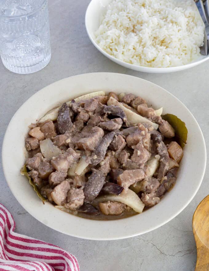 Kilawing Labanos at Baboy in a white serving bowl with a plate of rice in the background.