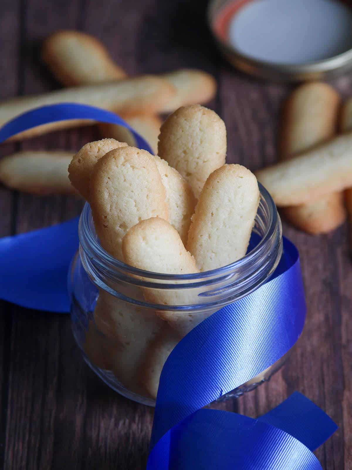 Filipino cat's tongue cookies in a glass jar with blue ribbon