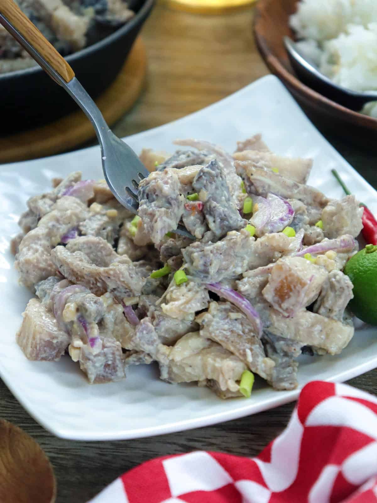 eating warek-warek on a white plate with a fork.