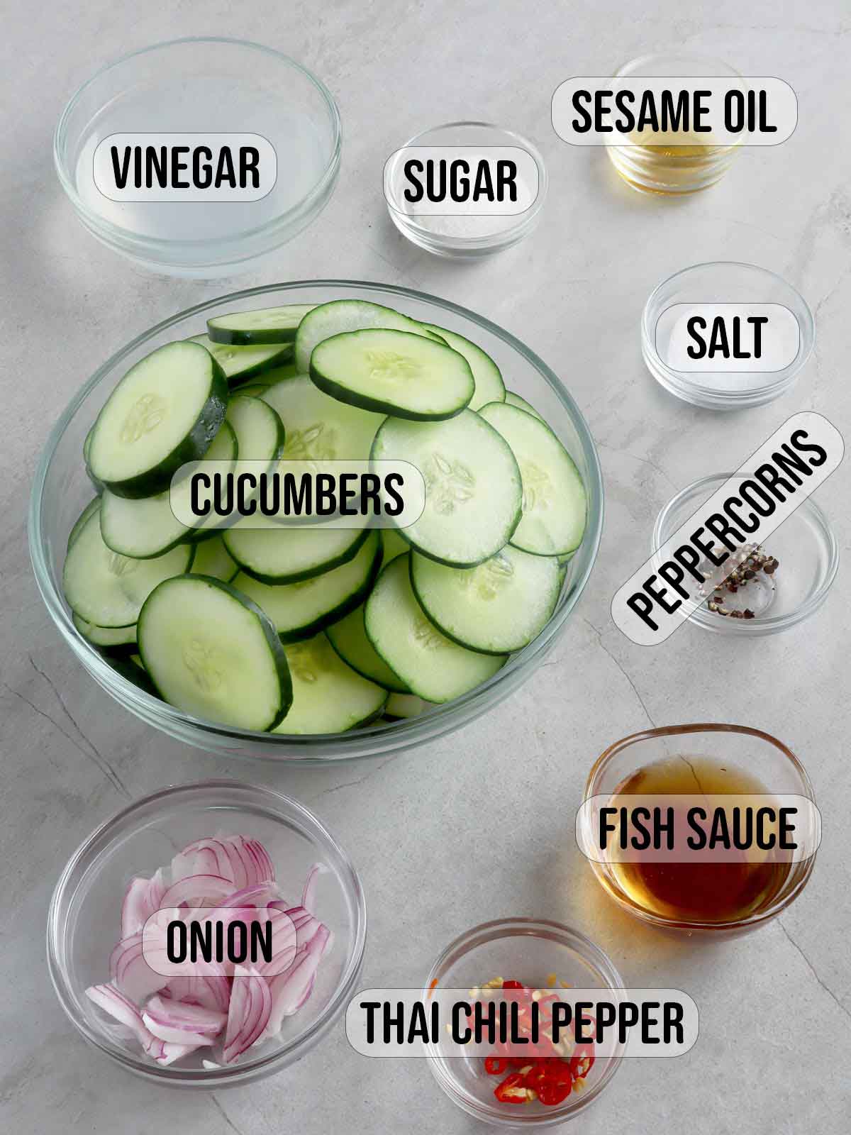 sliced cucumbers, chopped red onions, chopped chili peppers, fish sauce, sugar, salt, pepper in individual bowls.