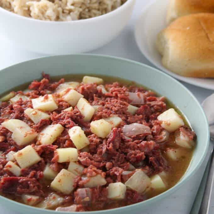 Ginisang Corned Beef in a serving bowl with pandesal and steamed rice on the side