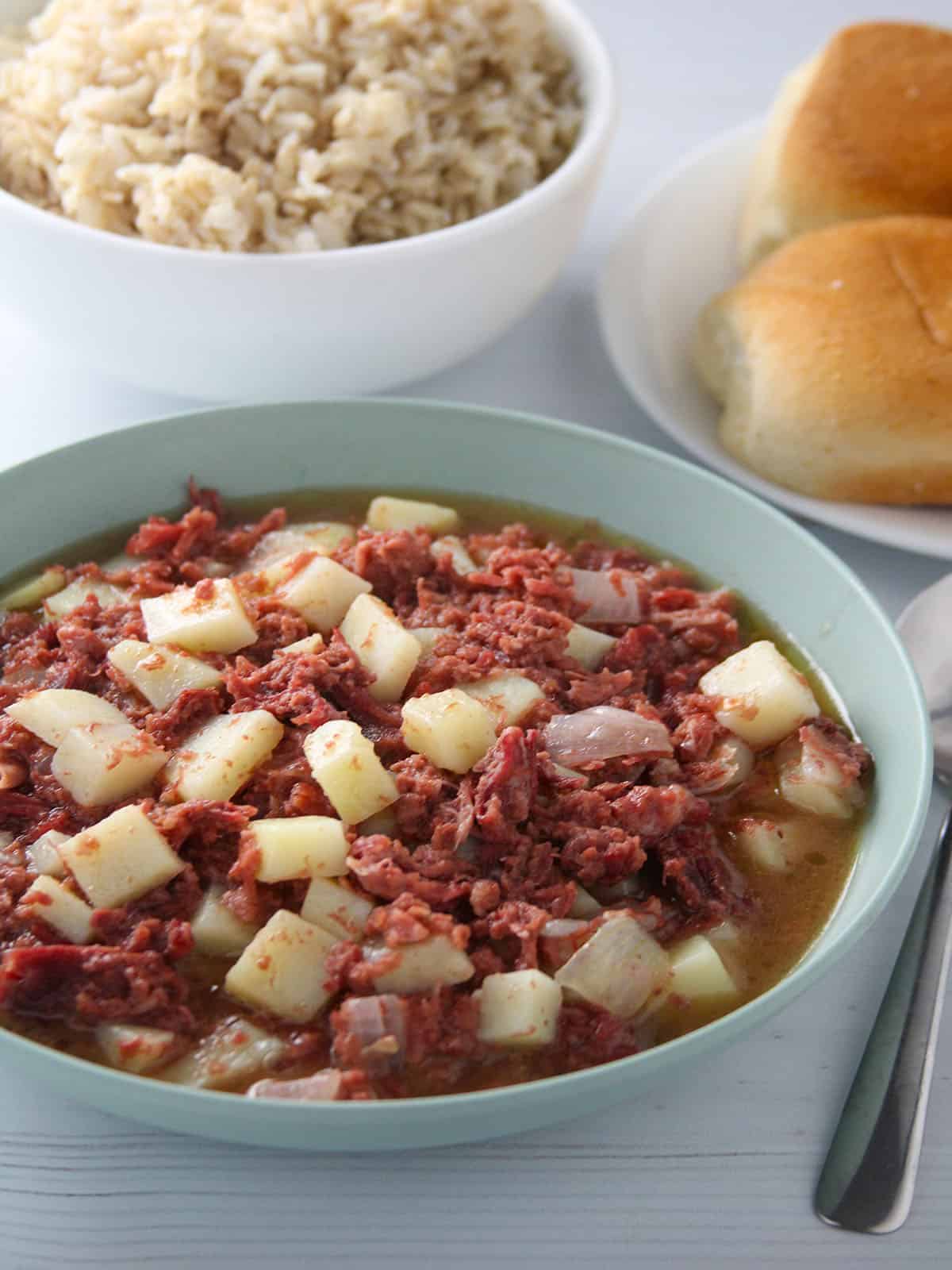 Ginisang Corned Beef in a serving bowl with pandesal and steamed rice on the side