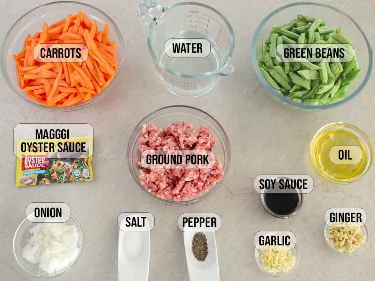 ground pork, green beans, carrots, garlic, ginger, onions, water, soy sauce, maggi oyster sauce packet, oil, salt, pepper in bowls.