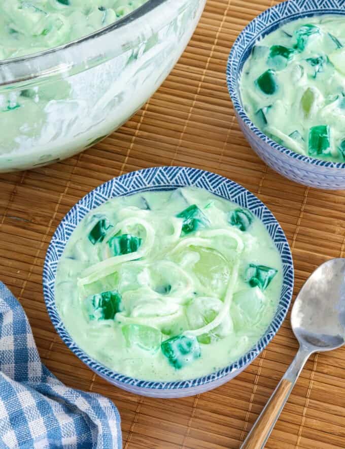Buko Pandan Salad in a clear glass bowl and in small blue bowls with spoon in the background.