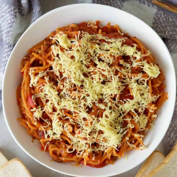 Instant Pot Filipino-style Spaghetti with shredded cheese in a white serving bowl