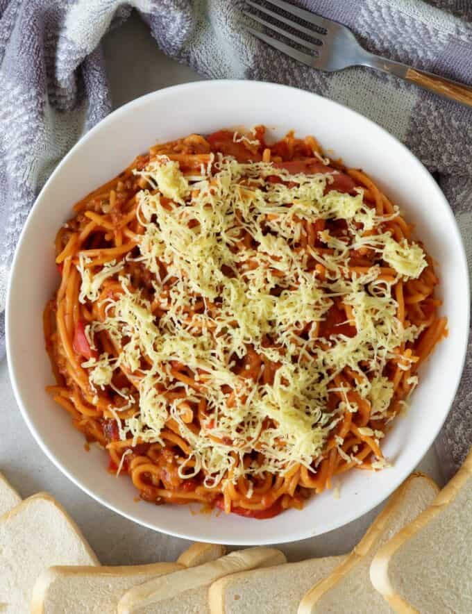 Instant Pot Filipino-style Spaghetti with shredded cheese in a white serving bowl