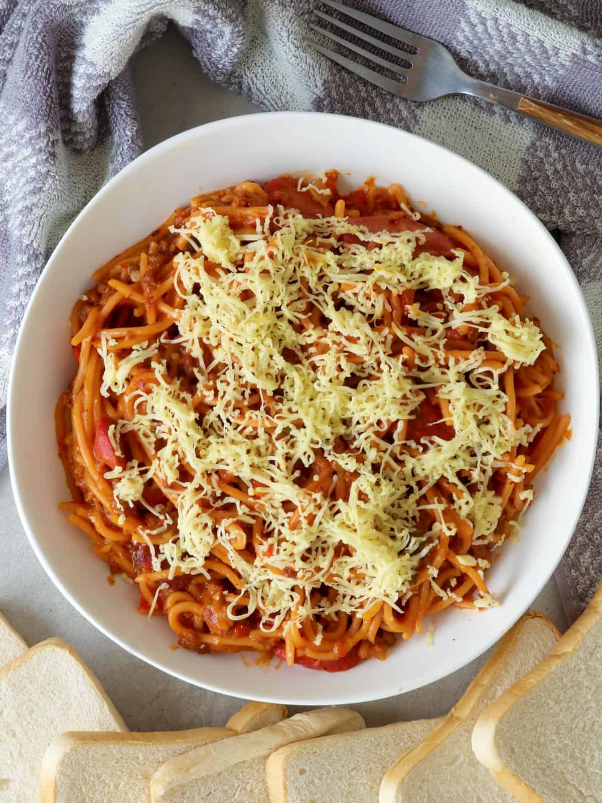 Instant Pot Filipino-style Spaghetti with shredded cheese in a white serving bowl