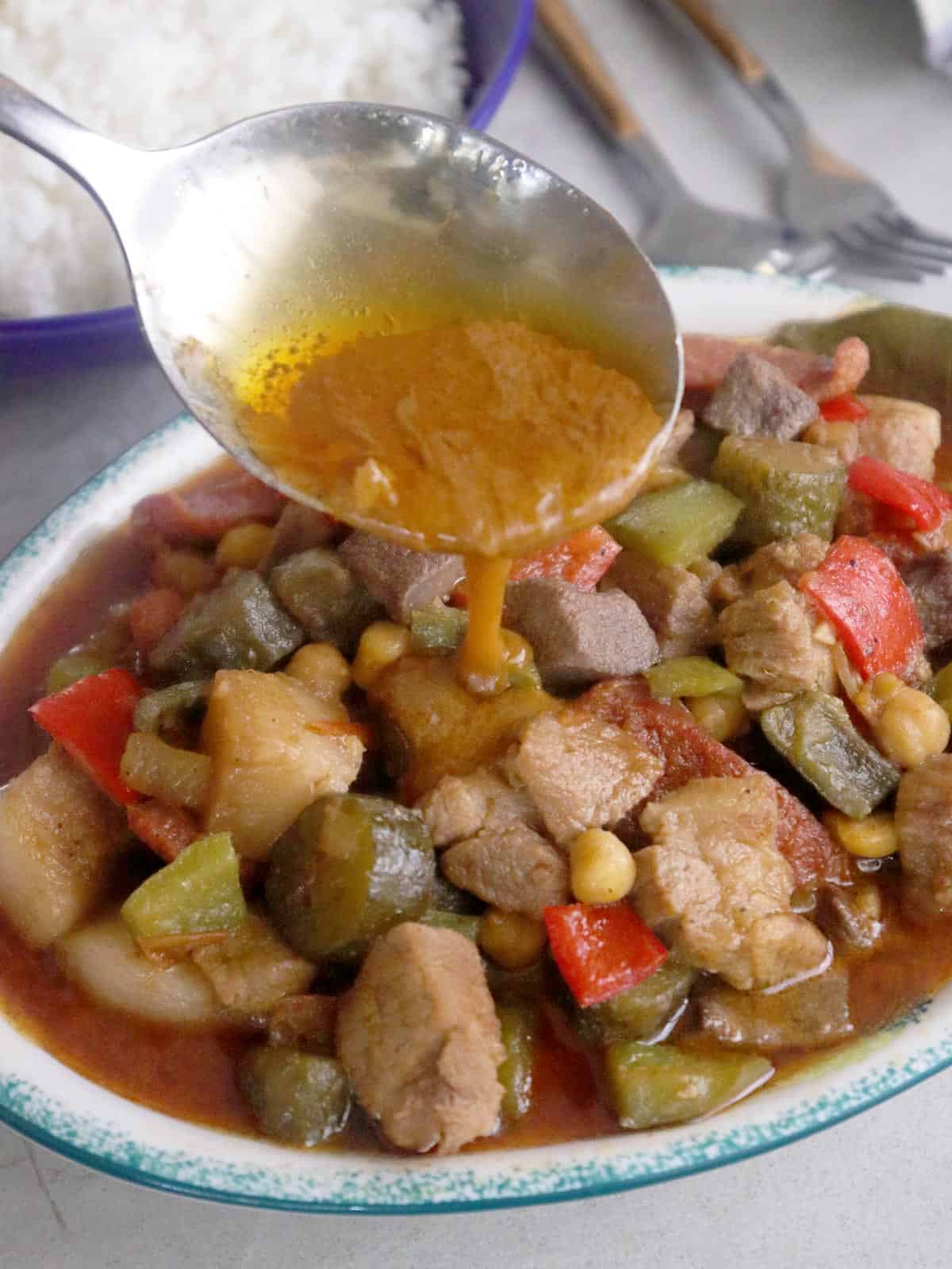 pouring sauce on a platter of Marikina menudo