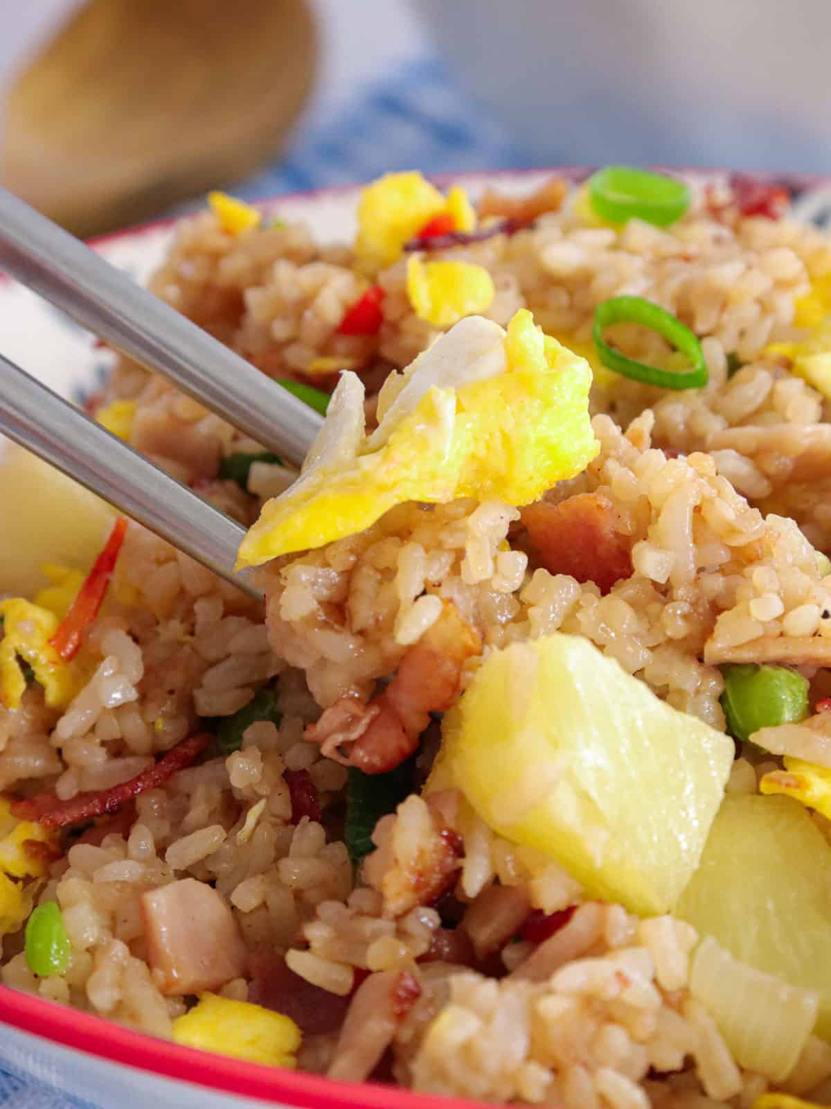 eating fried rice with ham and pineapples with chopsticks from a bowl.