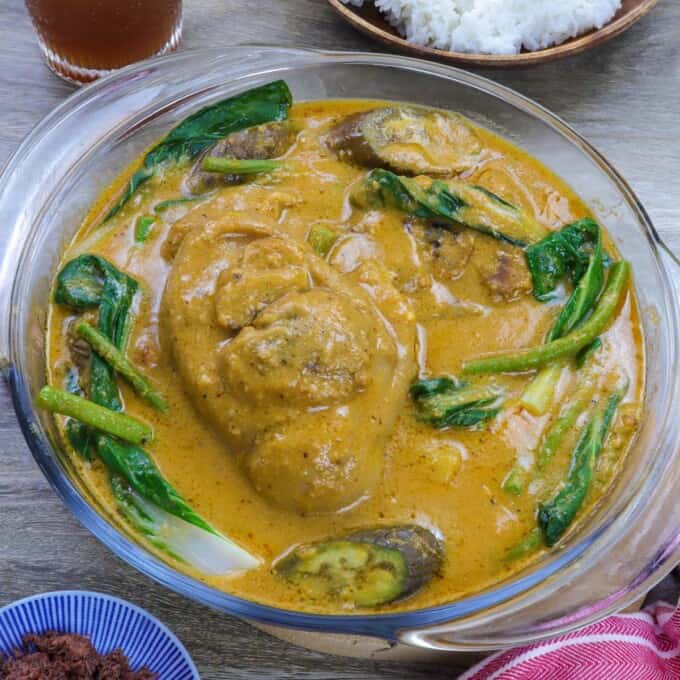 Pork kare kare in a clear glass bowl with steamed rice and ginisang bagoong on the side