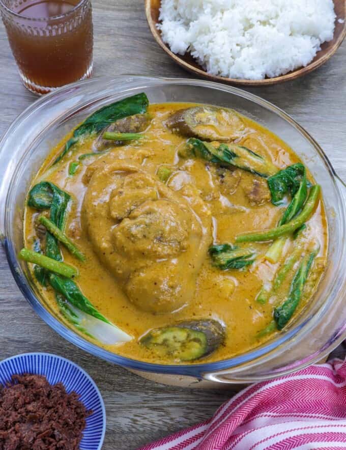 Pork kare kare in a clear glass bowl with steamed rice and ginisang bagoong on the side