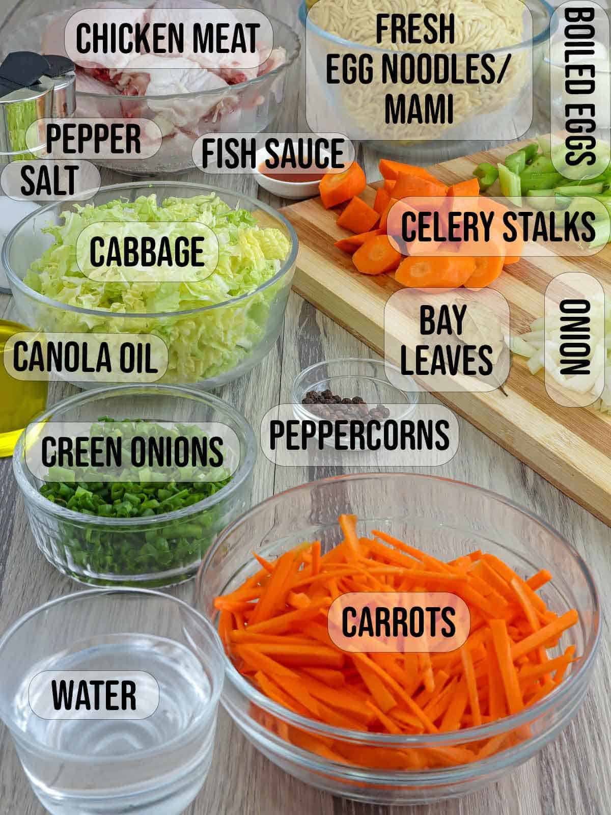 carrots, cabbage, eggs, water, celery, noodles, chicken, oil, salt, peppercorns, garlic, onions, green onions in bowls.