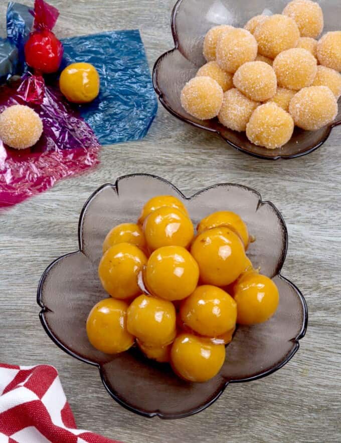 yema candies coated with caramel and in sugar in clear bowls.