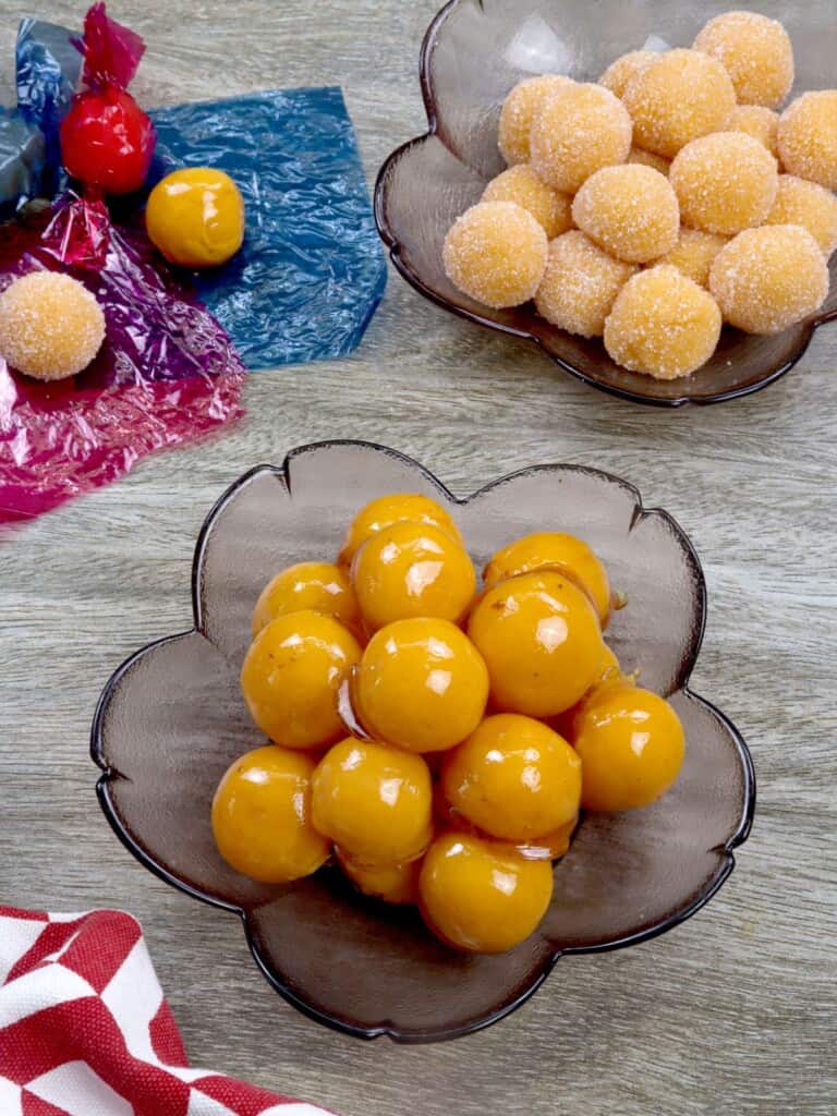 yema candies coated with caramel and in sugar in clear bowls.
