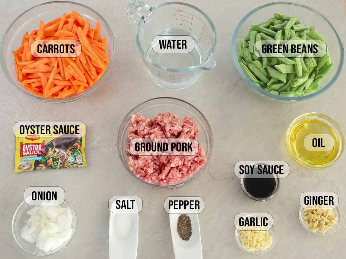 ground pork, green beans, carrots, garlic, ginger, onions, water, soy sauce, maggi oyster sauce packet, oil, salt, pepper in bowls.