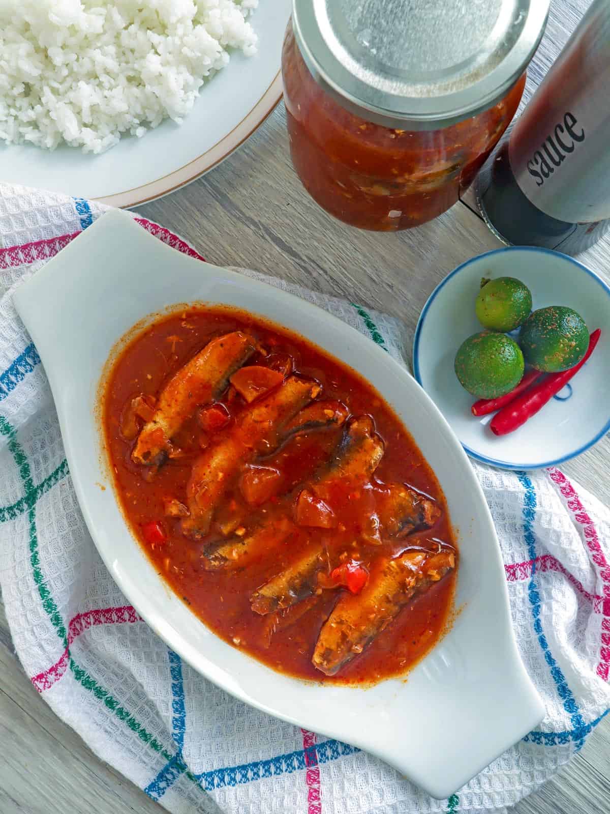 homemade sardines in tomato sauce in a white bowl with calamansi in the background.